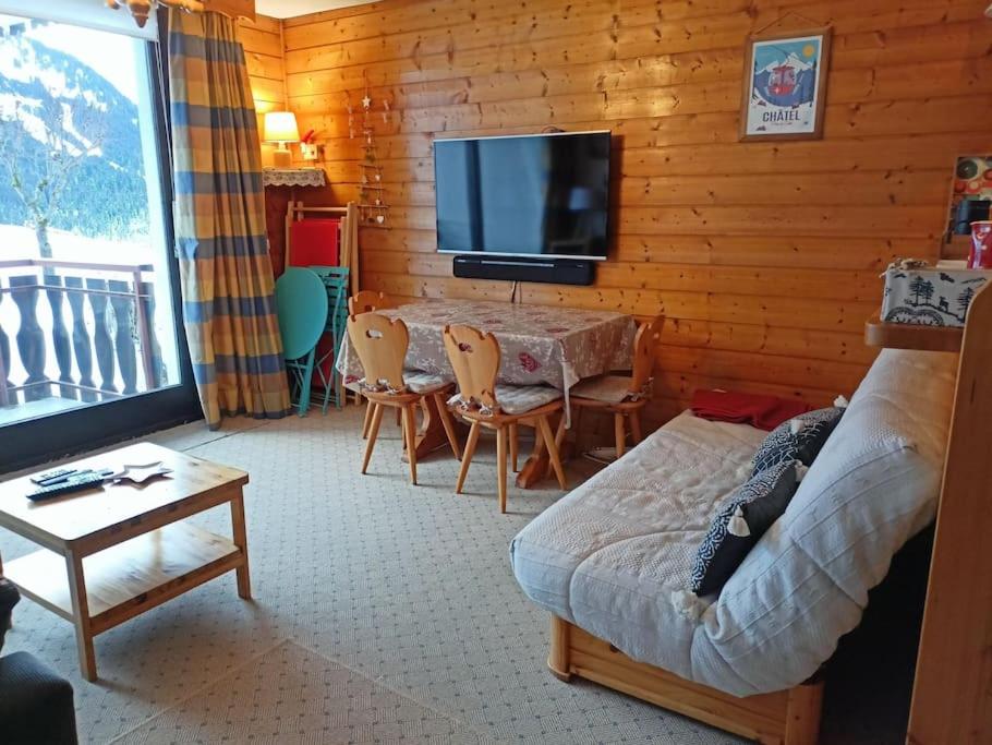 un salon avec une télévision et une table avec des chaises dans l'établissement Sylvia 46, joli studio ensoleillé en centre-ville - Multipass inclu, à Châtel