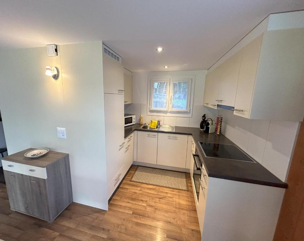 a small kitchen with white cabinets and a wooden floor at Chalet Gerbera in Wengen