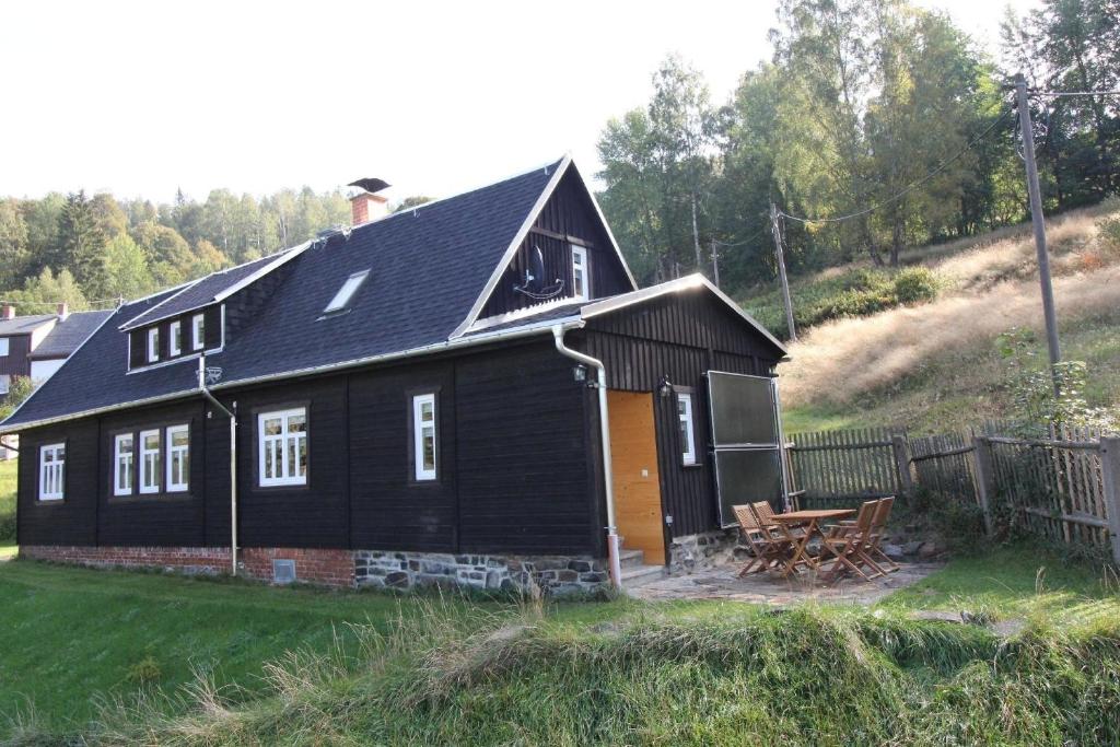 une maison noire avec une table de pique-nique devant dans l'établissement Ferienhaushälfte Gösselberg im Ferienhaus Anno Dazumal, wie zu Großmutters Zeiten, à Klingenthal