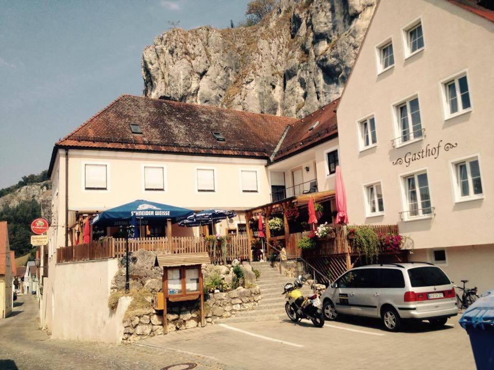 ein Auto, das vor einem Gebäude mit einem Berg parkt in der Unterkunft Gasthaus Felsenwastl in Essing