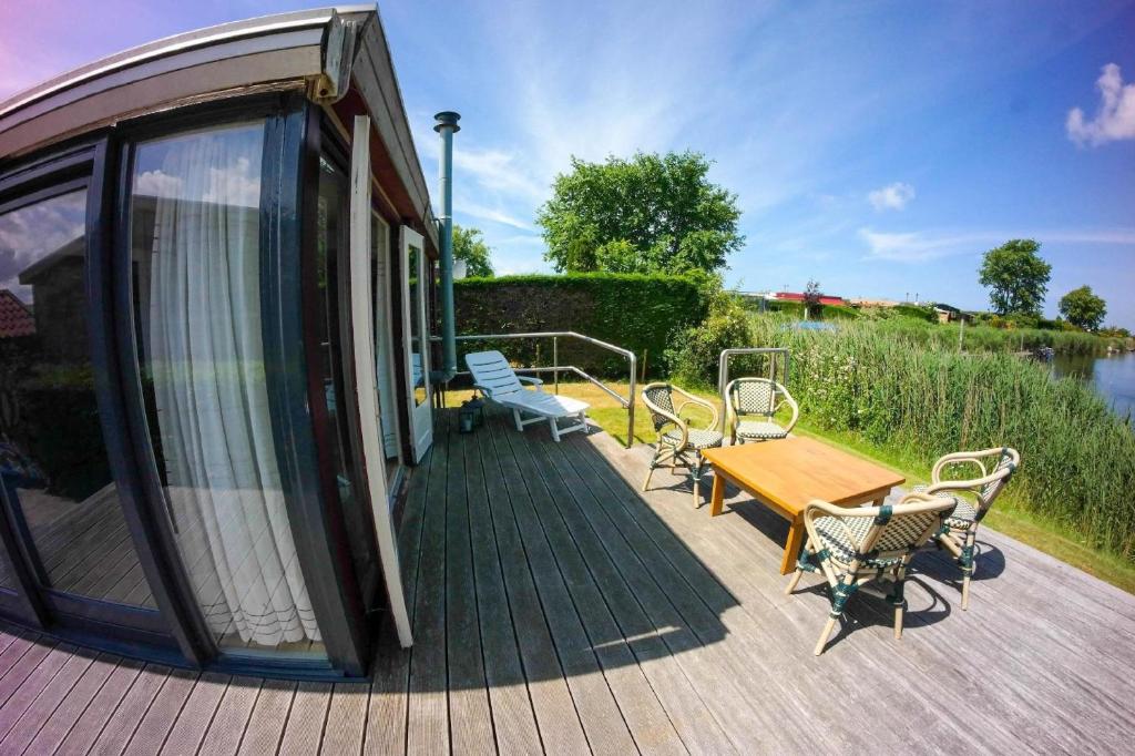 a house with a deck with a table and chairs at Chalet im Hafen mit Angelsteg infrarotsauna in Anjum