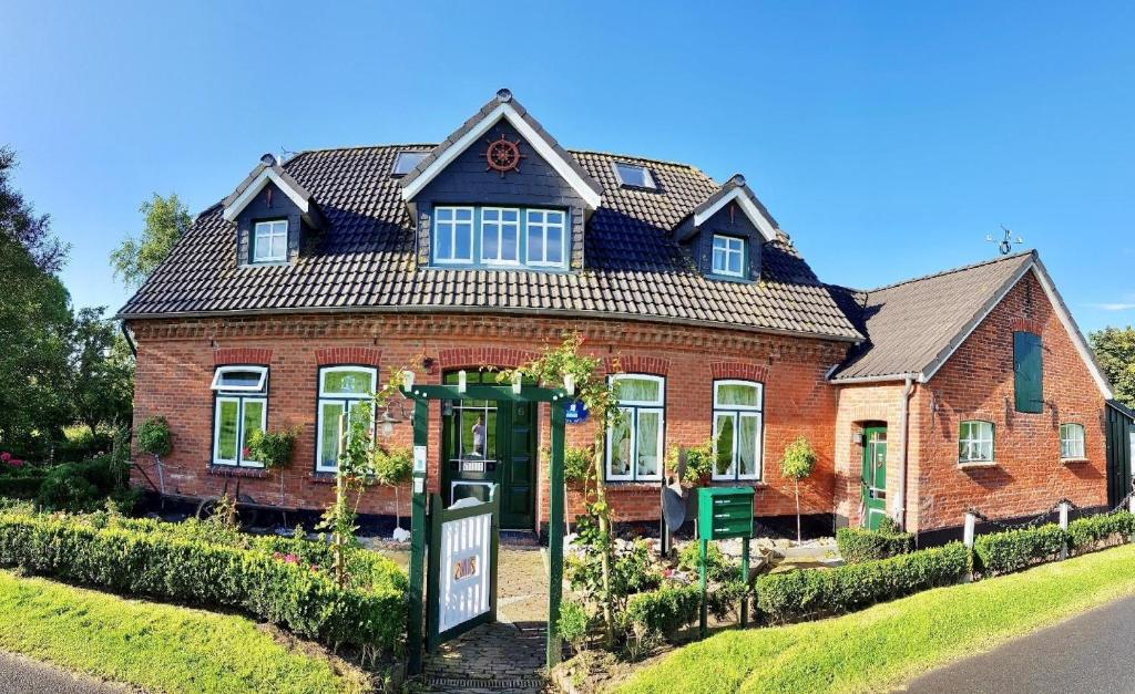 une maison en briques rouges avec un panneau devant dans l'établissement Das Marschenhaus, à Butjadingen