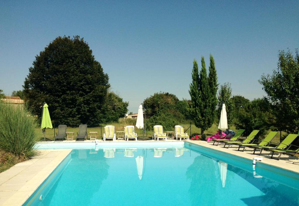 a swimming pool with chairs and umbrellas at La Galerie gîte climatisé 4 chambres 8 personnes, 2 salles d'eau, 2 WC, WIFI, parking, piscine chauffée à partager, animaux acceptés, Gîte en pleine nature in Lorignac