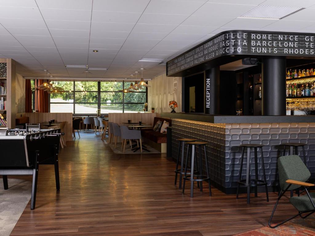 a restaurant with a bar with tables and chairs at ibis Styles Lille Aéroport in Lesquin