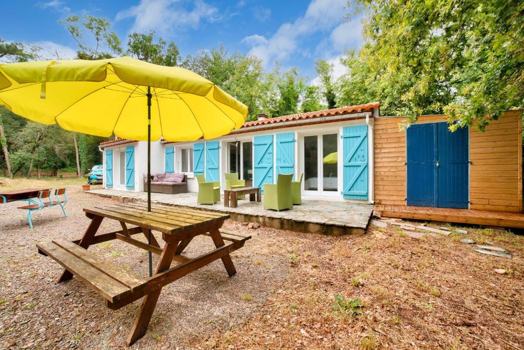 a picnic table with an umbrella in front of a cabin at 850m de la plage maison neuve pour 6 en foret in Saint-Vincent-sur-Jard