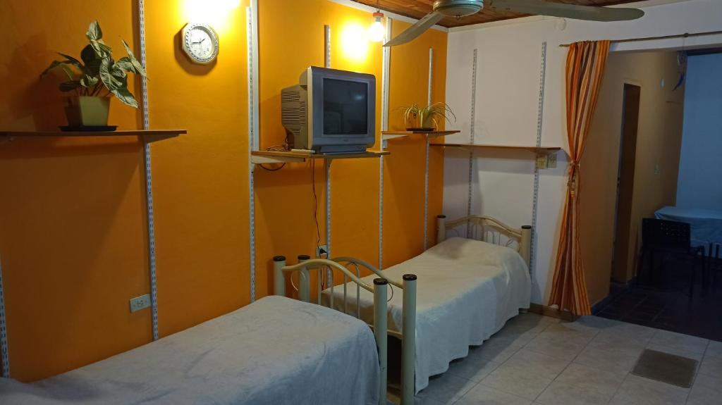 a room with two beds and a tv on a wall at Departamento familiar in Gualeguaychú