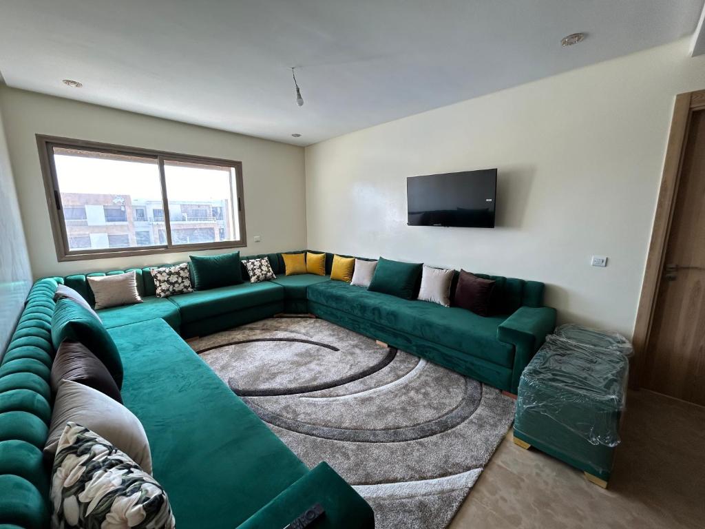 a living room with a green couch and a flat screen tv at Malaga Beach El Mansouria in Mansouria