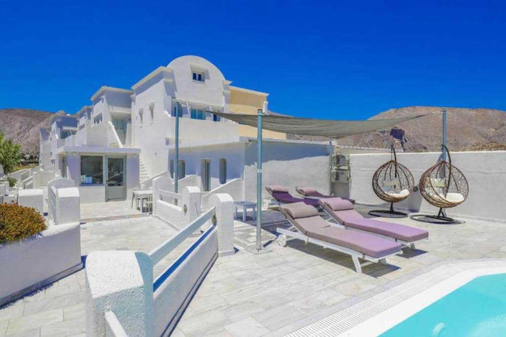 una villa con piscina e sedie a sdraio viola di Perissa BeachFront Rooms a Perissa