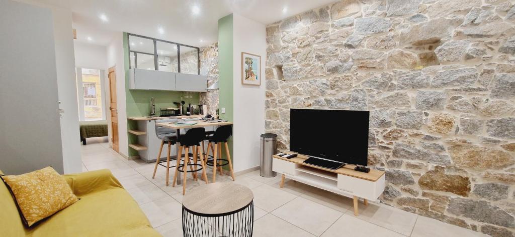 a living room with a tv and a stone wall at Appartement plein de charme - Ajaccio hyper centre in Ajaccio