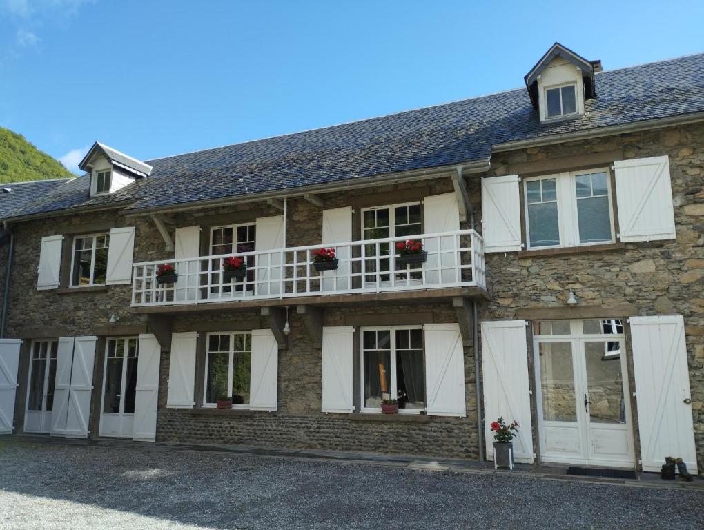 a large stone house with white doors and windows at Maison Fouga in Cadéac