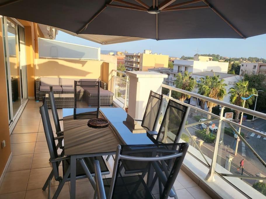 un balcon avec une table, des chaises et un parasol dans l'établissement Magnifique appartement en centre-ville av parking, à Cavalaire-sur-Mer