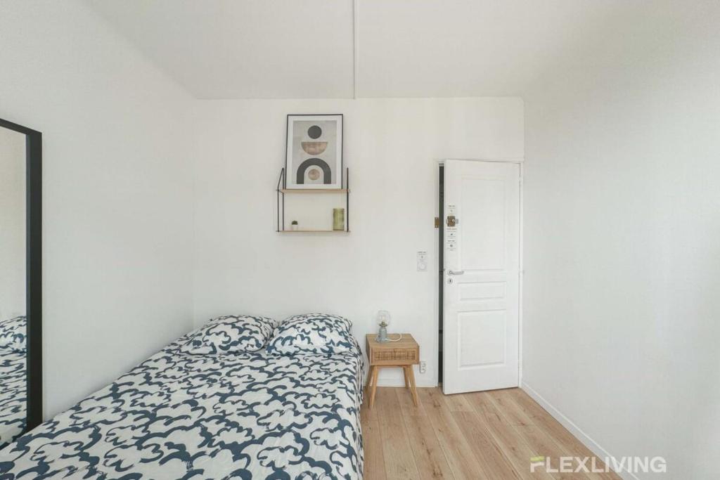 - une chambre blanche avec un lit et une petite table dans l'établissement Flexliving - room - Houel, à Paris