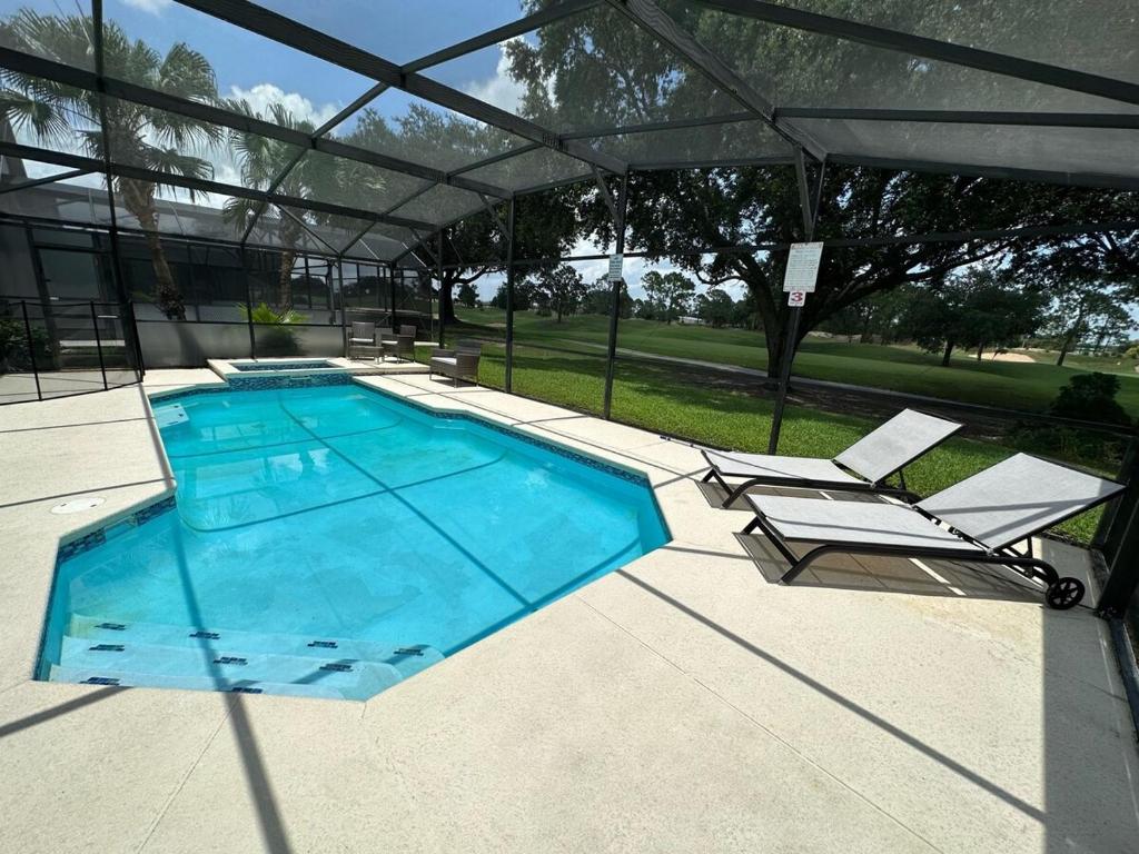 a large swimming pool with two chairs and an umbrella at Beautifully Remodeled Home - Southen Dunes Golf Course Views in Haines City
