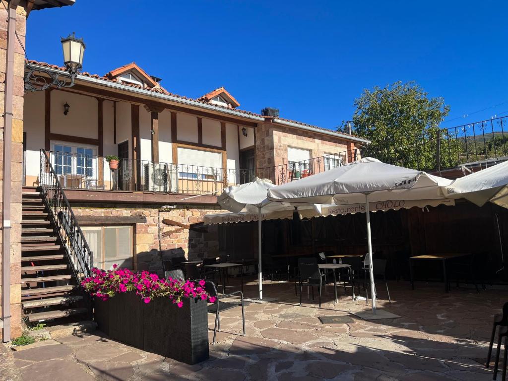 a building with tables and umbrellas in front of it at Apartamento Cholo in Brañosera