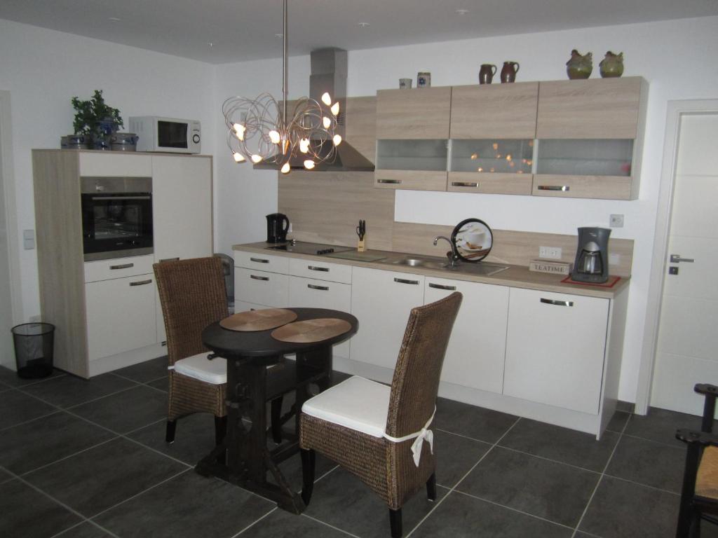 クサンテンにあるFerienwohnung Mauritiusstraßeの白いキャビネット、テーブルと椅子付きのキッチンが備わります。