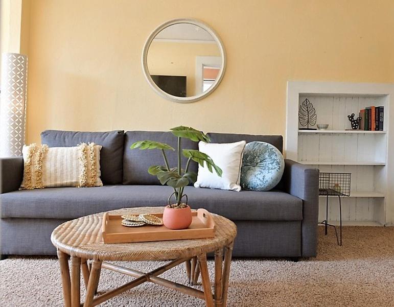 a living room with a blue couch and a round mirror at #StayinMyDistrict Heritage House Apt in Coos Bay