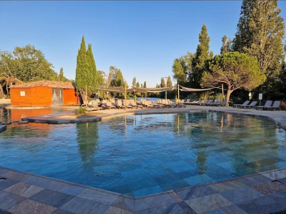- une grande piscine avec des chaises dans un complexe dans l'établissement Le Village Camarguais pour 4 avec piscine et animations, idéal famille, à Arles
