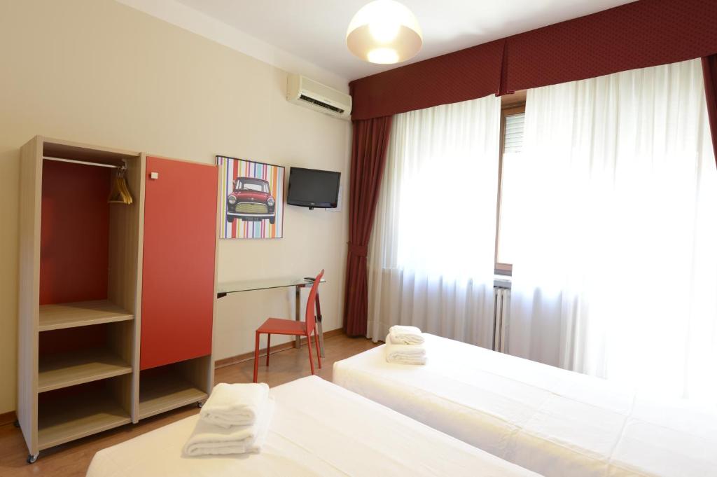 a hotel room with two beds and a desk at Hotel Tourist in Turin