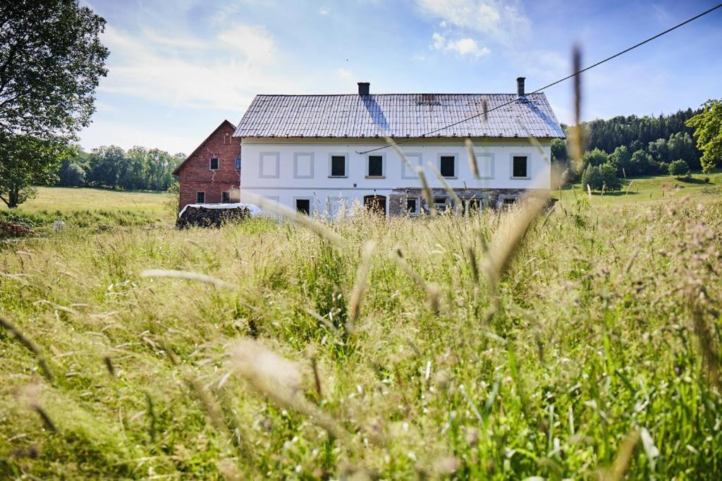 an old white house in the middle of a field at Statek 85 in Mařenice