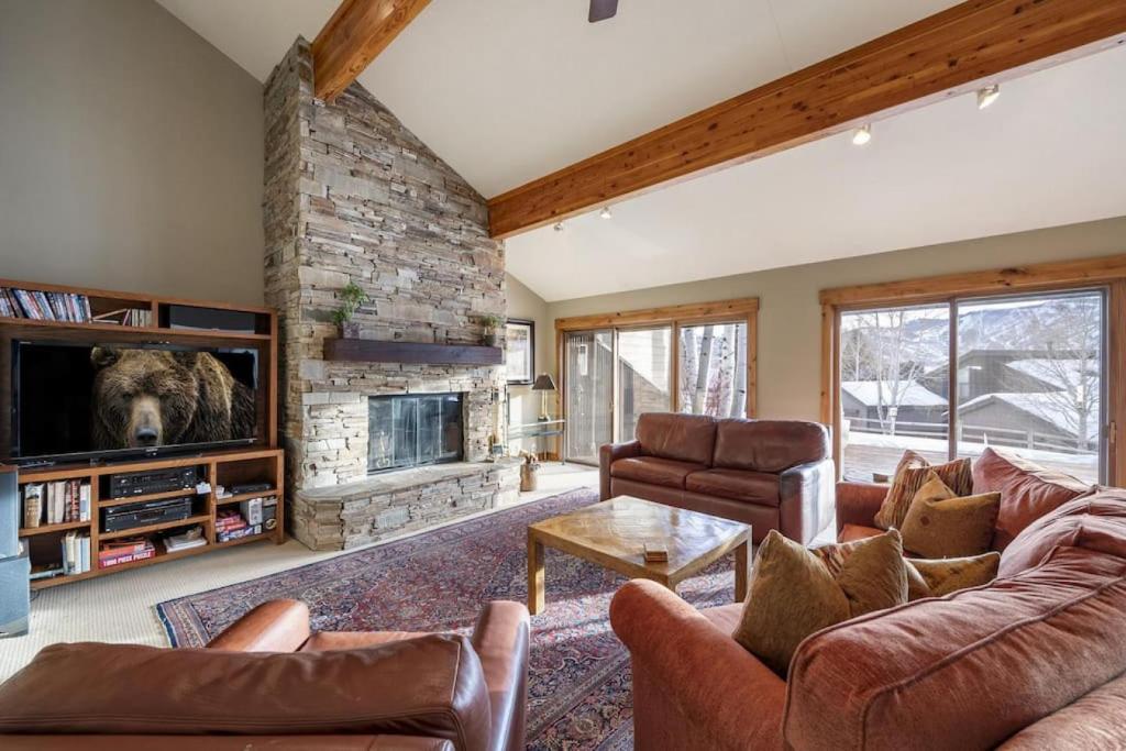a living room with couches and a stone fireplace at Rustic Elegance Located near PCM with Hot Tub in Park City