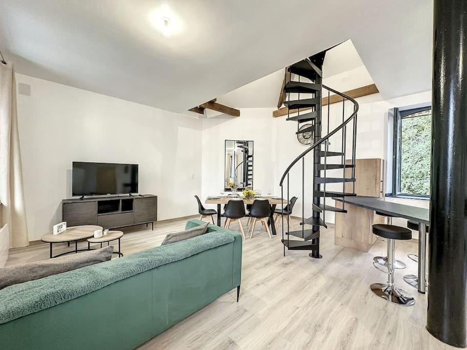 a living room with a green couch and a spiral staircase at Charmant Duplex au Cœur Vosgien in Charmes