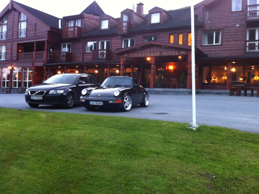 two cars parked in a parking lot in front of a building at Vossestrand Hotel and Apartments in Myrkdalen 