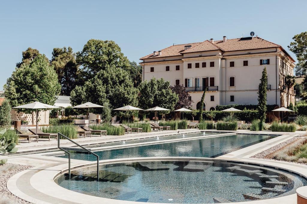 une piscine en face d'un bâtiment avec des tables et des parasols dans l'établissement Villa Corallo, à SantʼOmero