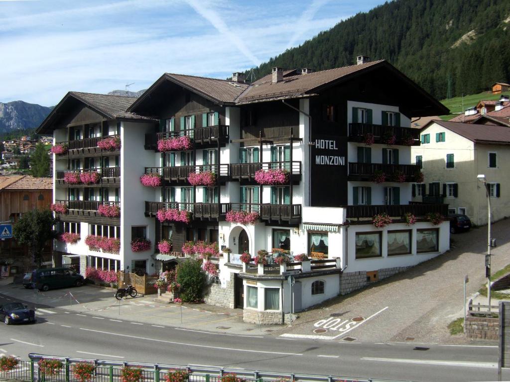 a building with flowers on the balconies on a street at GH Hotel Monzoni in Pozza di Fassa