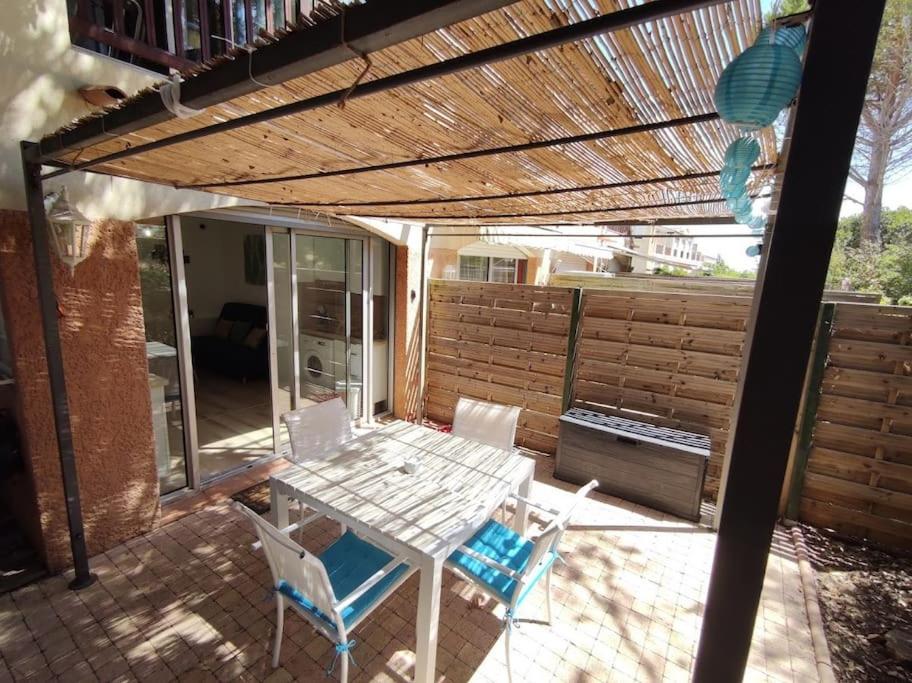 un patio avec une table et des chaises sous une pergola dans l'établissement Super logement pour 4 avec SPA privé, plages à proximité, piscine et jardin, à Sausset-les-Pins