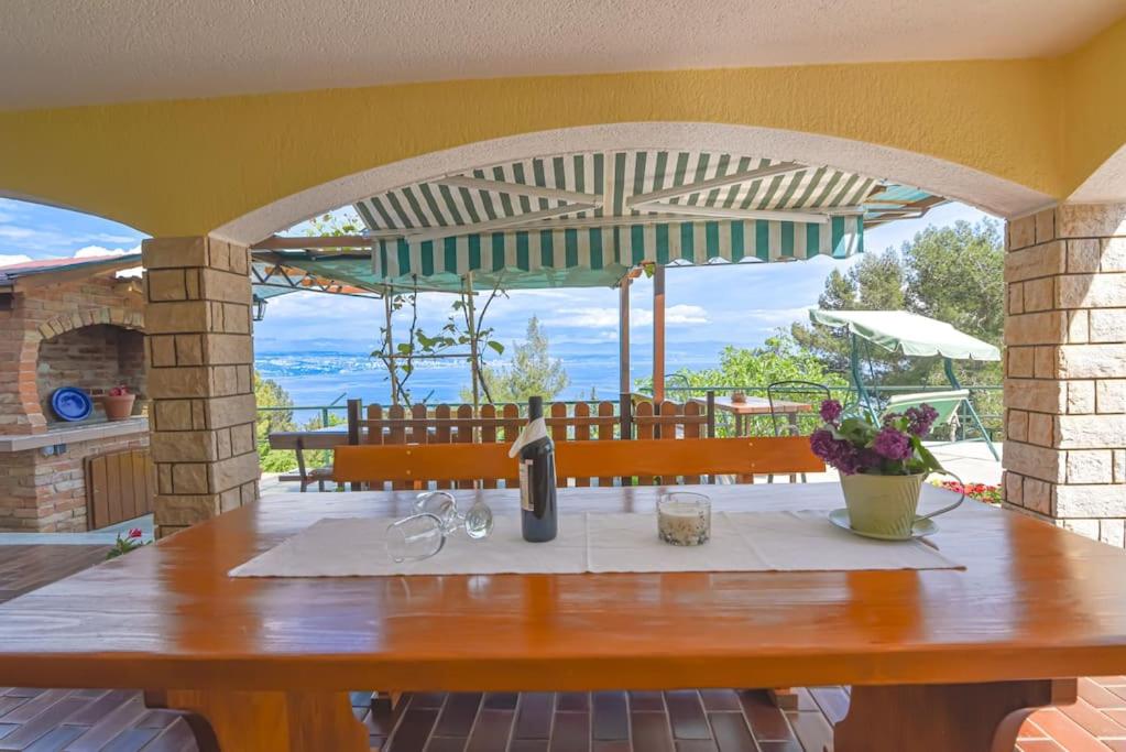 a table with a wine bottle and glasses on a patio at Apartment Brezina - Lovran - Liganj in Lovran