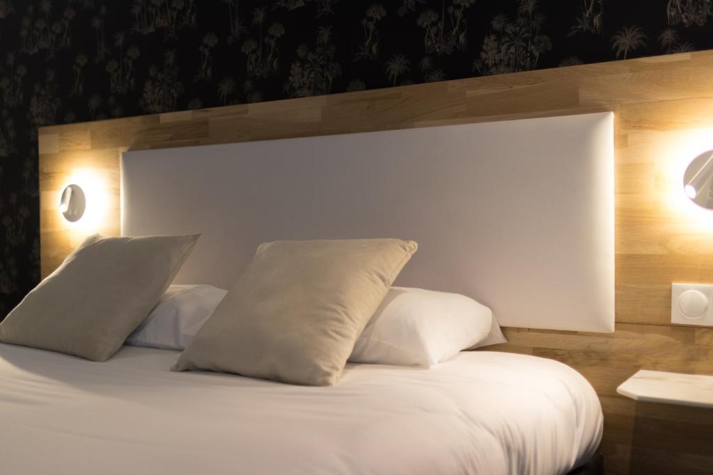 a white bed with two pillows on top of it at Brit Hotel Privil&egrave;ge Le Royal - Centre Gare in Troyes