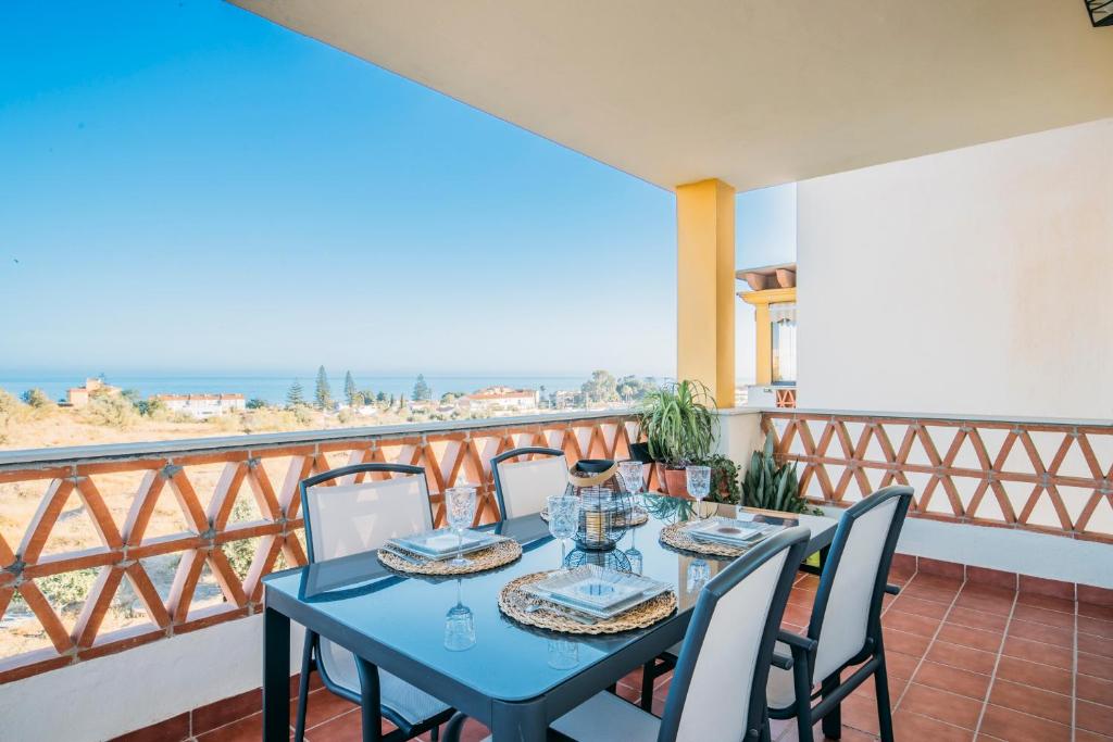 d'une table bleue et de chaises sur un balcon donnant sur l'océan. dans l'établissement El Rinconcito, à Torre de Benagalbón