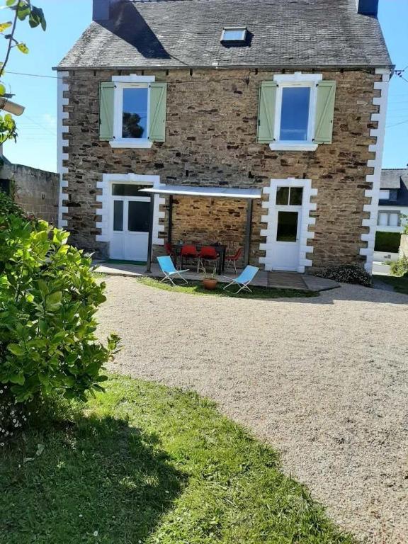 une maison en briques avec deux chaises et une table dans l'établissement Un rêve à la mer, à Plestin-les-Grèves
