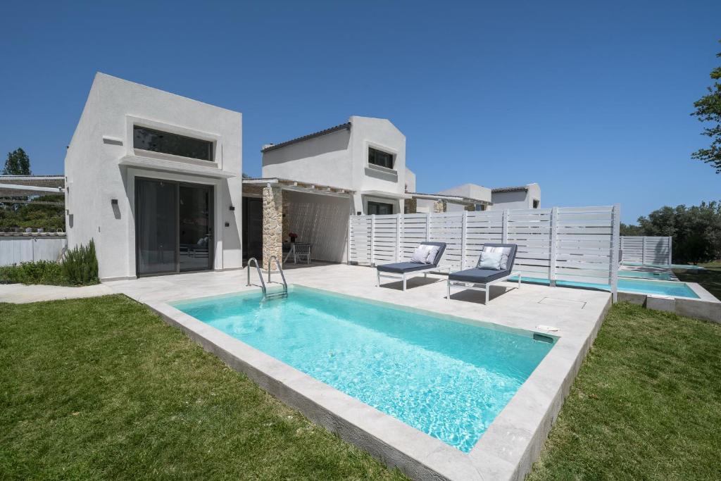 a villa with a swimming pool in front of a house at Astrum Luxury Suites in Vourvourou