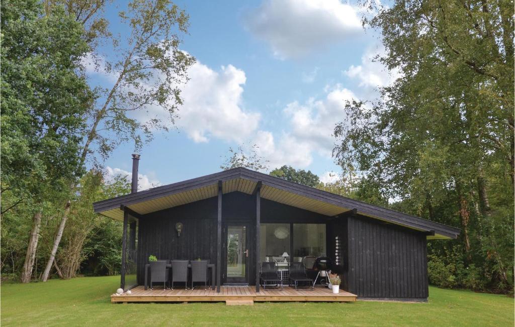 a black tiny house with a deck and chairs at Four-Bedroom Holiday Home In Hornbak in Hornbæk