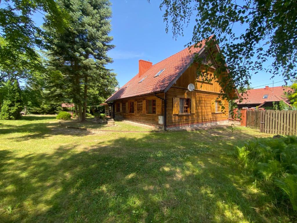 an old house with a red roof on a yard at Zabytkowa Karczma in Jedwabno