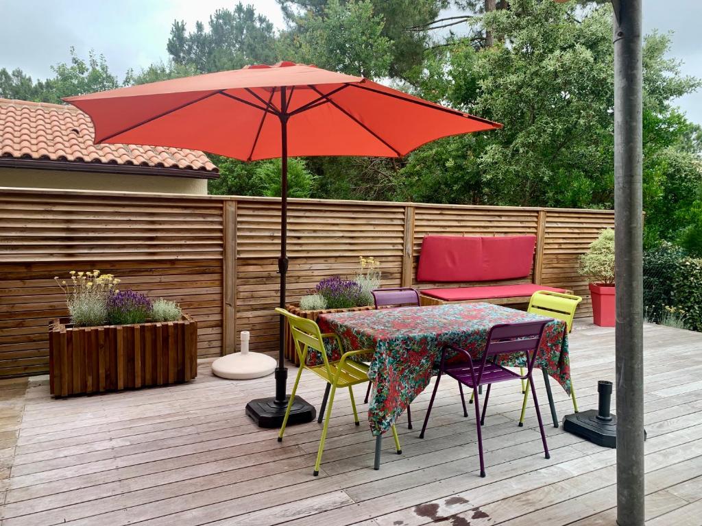 une table et des chaises avec un parasol sur une terrasse dans l'établissement Maison au calme dans le golf de Lacanau, à Lacanau