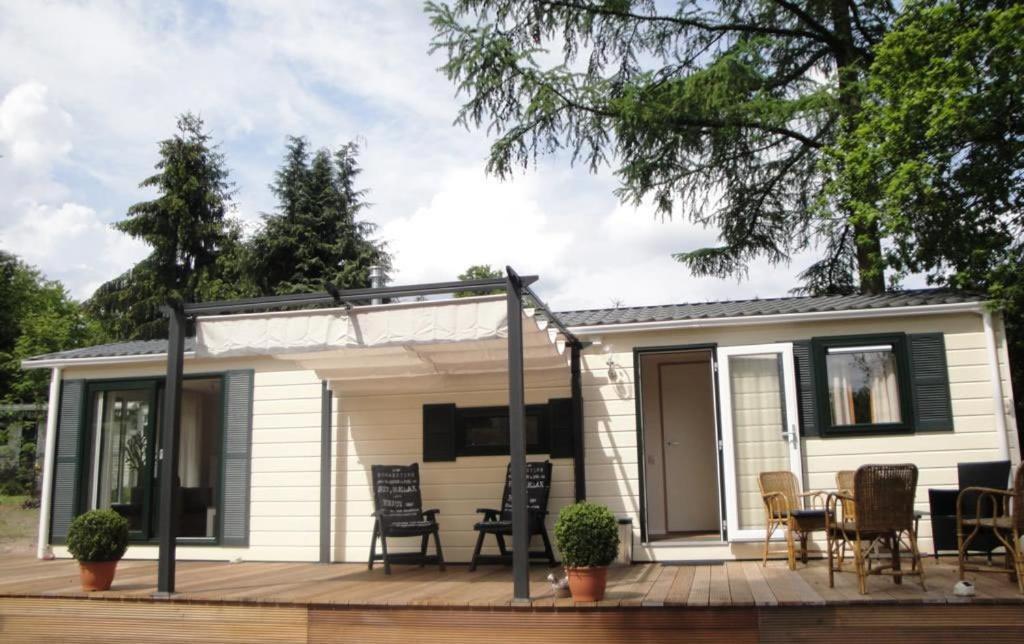 een tiny house met een veranda en een terras bij Sunnychalet in Beekbergen