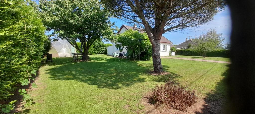 - une vue sur une cour arborée et une maison dans l'établissement Le calme et l'air marin, à Gonneville-en-Auge