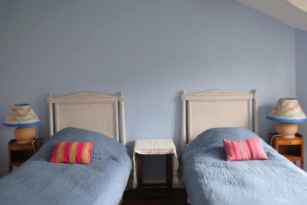 two beds with pillows in a room with blue walls at Le Ragois in Richelieu