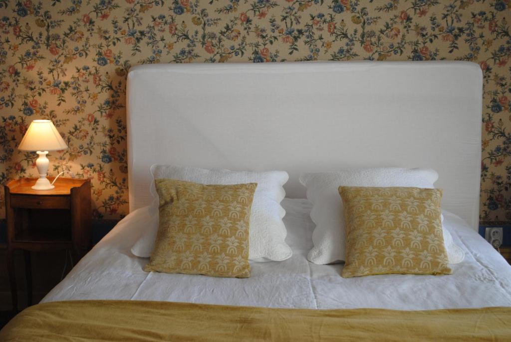 a white bed with two pillows and a white headboard at Le Ragois in Richelieu