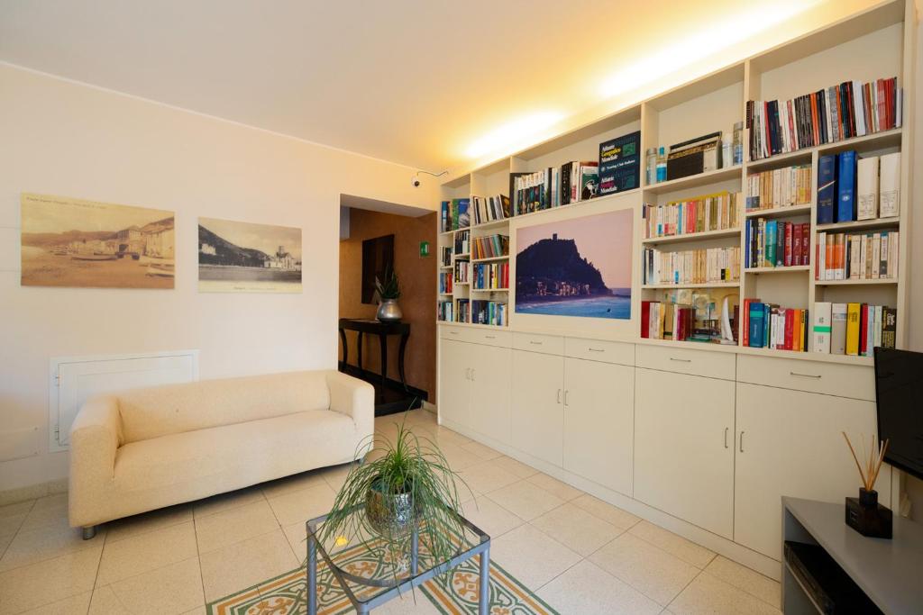 a living room with a couch and shelves of books at Hotel Albatros Varigotti in Varigotti