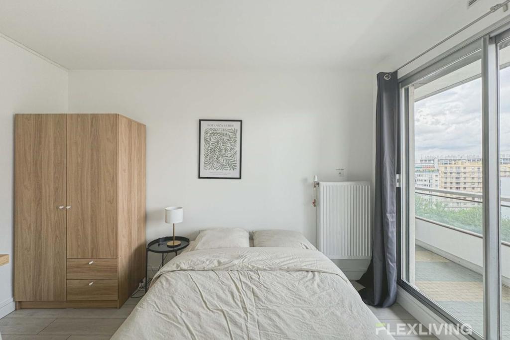 une chambre avec un lit et une grande fenêtre dans l'établissement Flexliving - room - Mouchez, à Paris