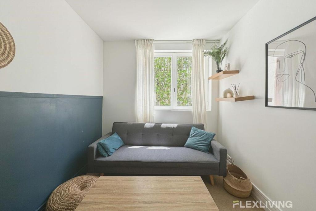 un salon avec un canapé et une fenêtre dans l'établissement Flexliving - room - Friant, à Paris
