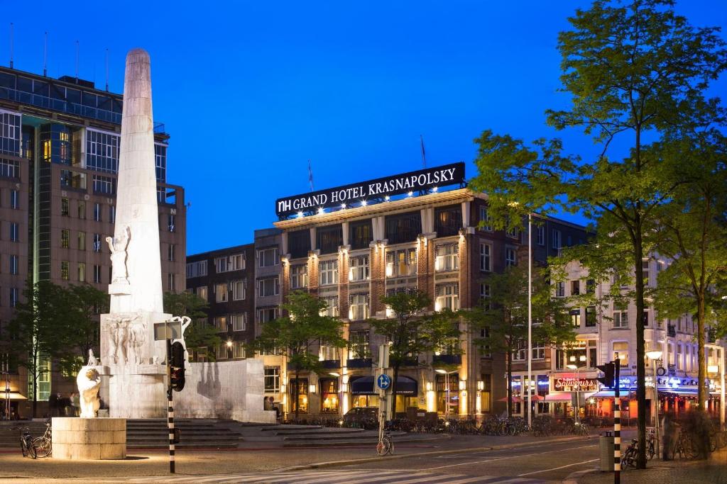 un edificio con un monumento delante de él en Krasnapolsky Apartments, en Ámsterdam