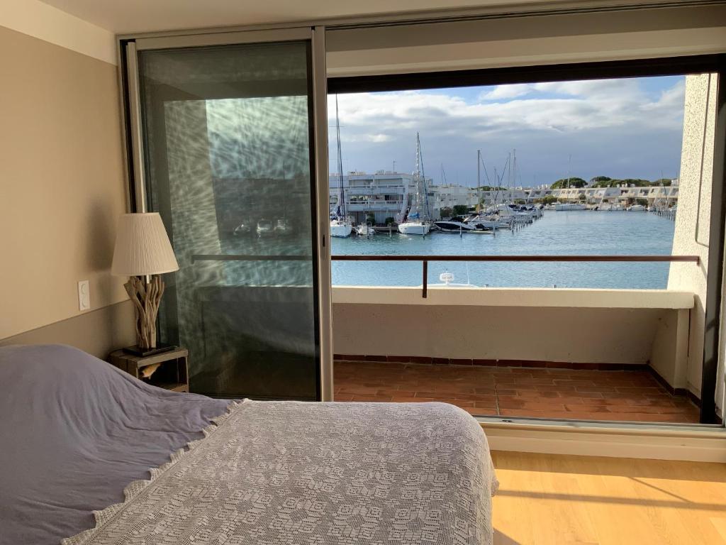 - une chambre avec une grande fenêtre donnant sur le port de plaisance dans l'établissement marina avec son bateau, au Grau-du-Roi