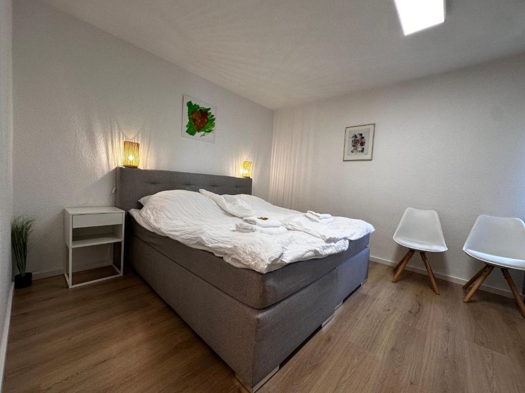 a bedroom with a bed and two white chairs at Premium Apartments Schwetzingen, Heidelberg, Speyer in Schwetzingen