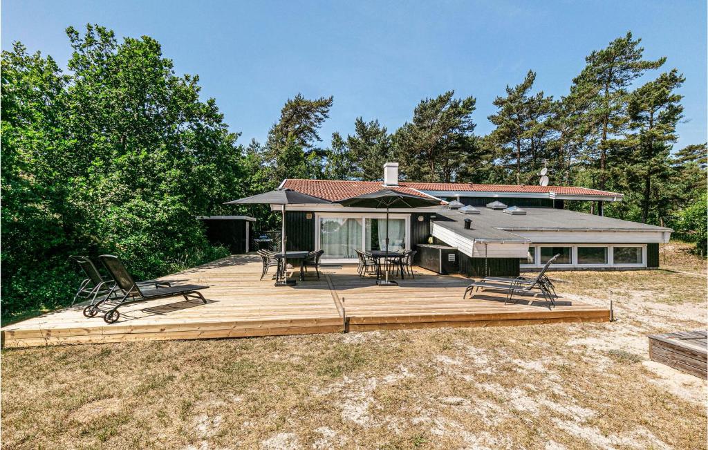 a house with a deck with chairs and an umbrella at Amazing Home In Nexø With Sauna in Snogebæk