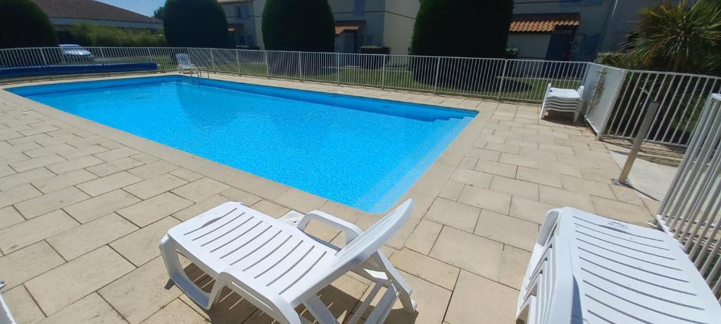 twee witte stoelen en een zwembad met bij Entre Golf et Mer in Pornic