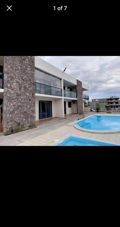 a large building with a swimming pool in front of it at The confidence in Mahébourg